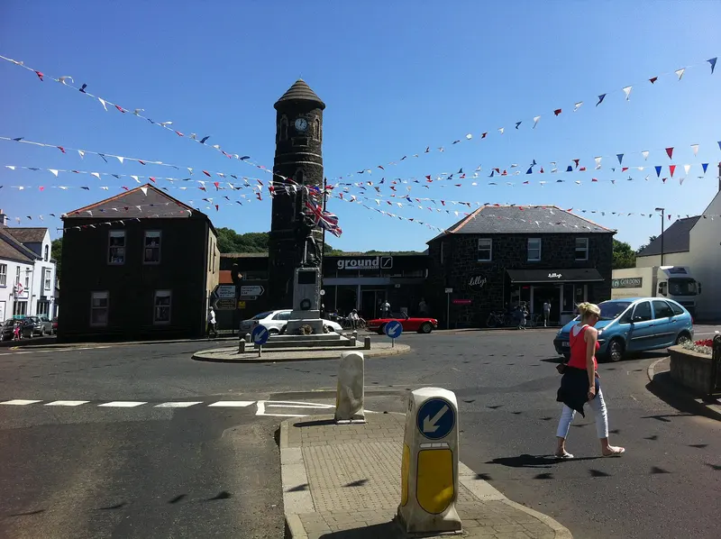 The centre of Bushmills village with its stone clock tower, strung with bunting under a blue sky