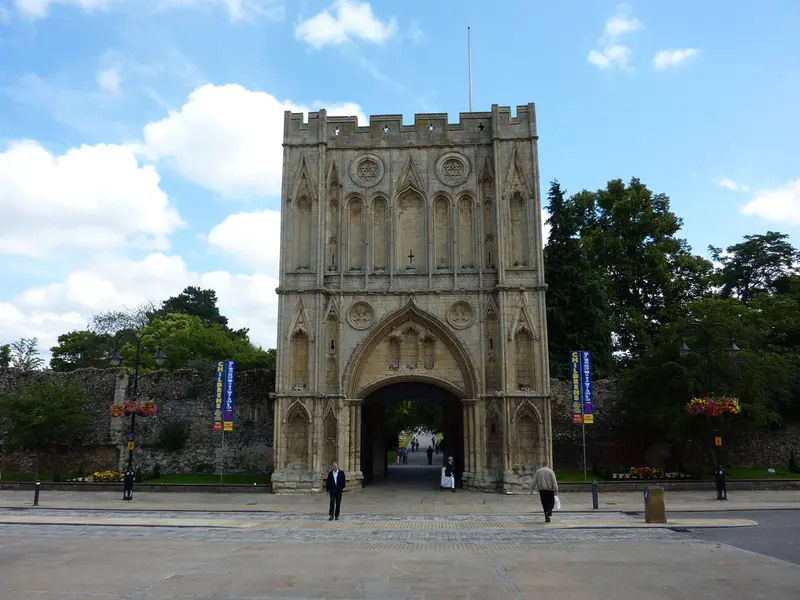 The tall medieval stone Abbey Gate in Bury St Edmunds facing the open square of Angel Hill under a blue sky