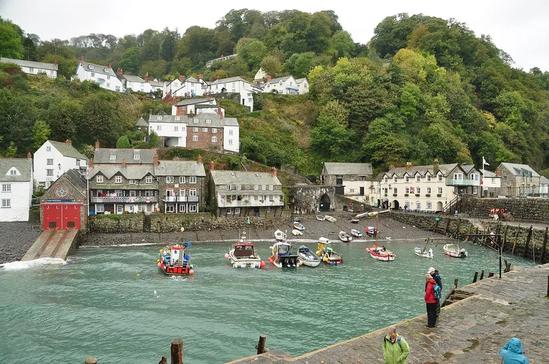 The small stone harbour at Clovelly with moored boats, whitewashed cottages and wooded cliffs behind