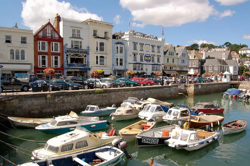 Small boats moored in the Boat Float harbour basin, with colourful townhouses and shops behind under a sunny sky