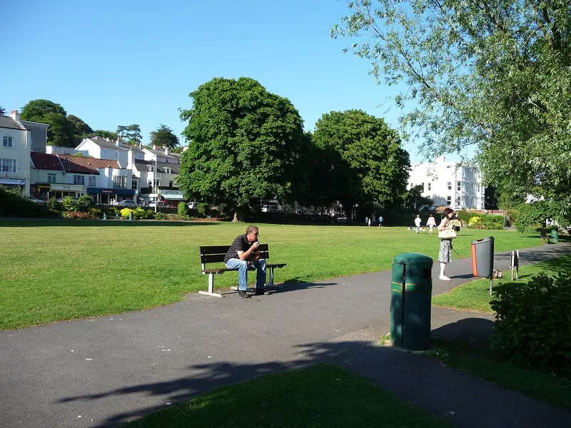 A sunny green lawn with paths, benches and trees in the centre of Dawlish