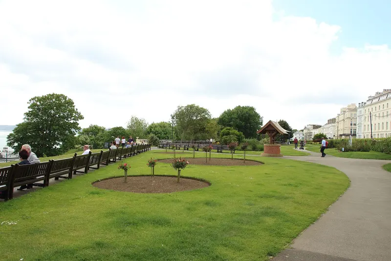 Lawns, flower beds and paths in Crescent Gardens, Filey, with a terrace of tall seafront houses beyond