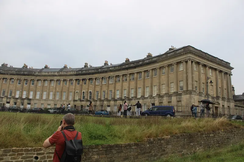 The sweeping Georgian terrace of the Royal Crescent seen across long grass in Royal Victoria Park