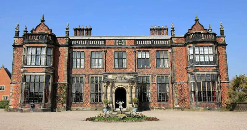 The red-brick Victorian front of Arley Hall, with gables and tall chimneys, behind a gravel forecourt