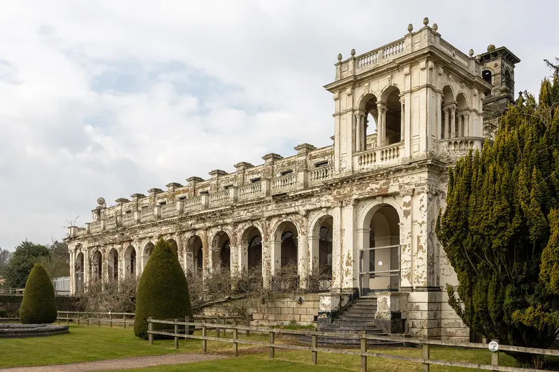 The ornate Italianate stone clock tower and arcaded wing that survive from Trentham Hall, beside a lawn