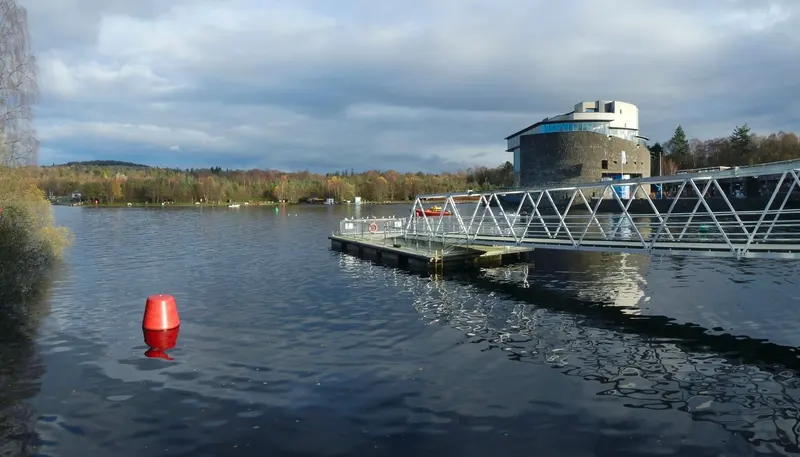 A jetty and the round Drumkinnon Tower on the shore of Loch Lomond at Balloch