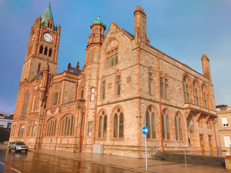 The red sandstone Guildhall in Derry~Londonderry with its clock tower, under a clear blue sky