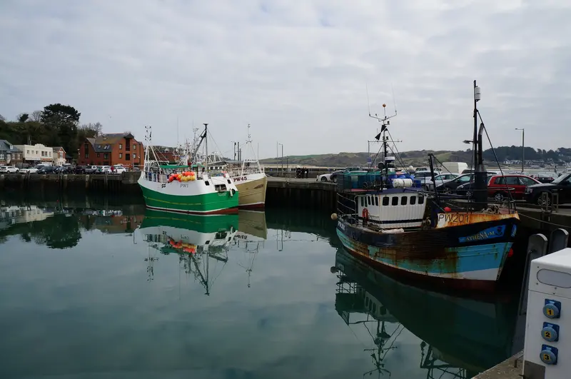 Fishing boats moored in Padstow's harbour, with quayside buildings and the Camel estuary beyond