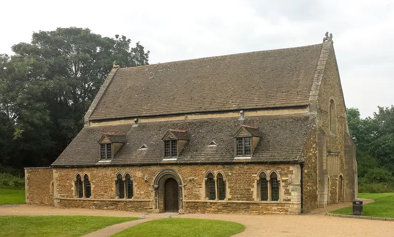 The stone Norman great hall of Oakham Castle on a lawn, with trees behind
