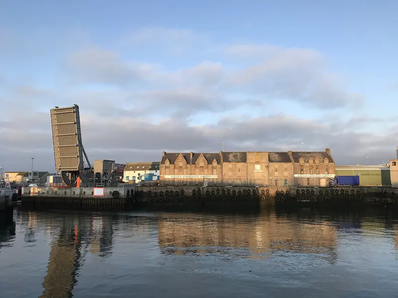 Boats and harbourside buildings reflected in the still water of Peterhead harbour
