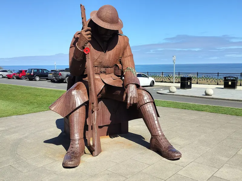 The large rusted-steel 'Tommy' statue of a seated First World War soldier on Terrace Green above the sea at Seaham