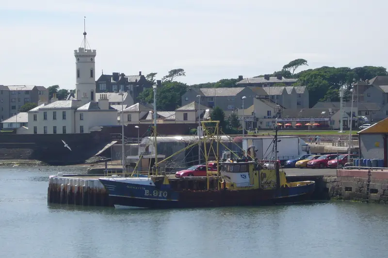 Fishing boats in Arbroath harbour with the white Signal Tower and harbourside buildings behind