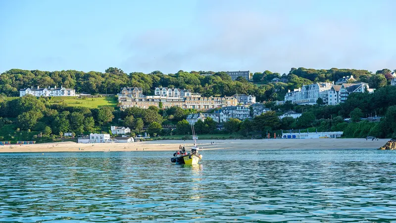 Turquoise sea and a curving sandy beach backed by wooded slopes and white houses