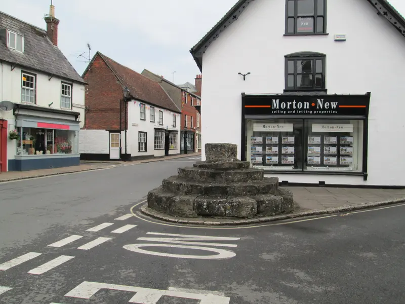 The old market cross on a small traffic island among shops and houses in Sturminster Newton