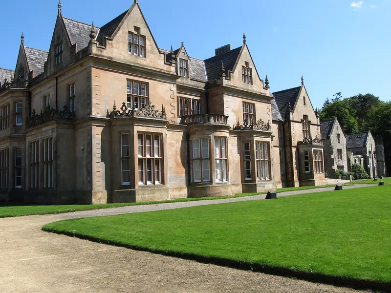 The gabled Victorian stone mansion of Bangor Castle, now the town hall, beside a sunny lawn