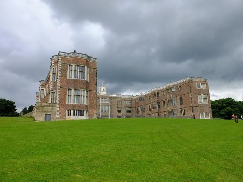 The long red-brick Tudor-Jacobean front of Temple Newsam House above a sloping green lawn