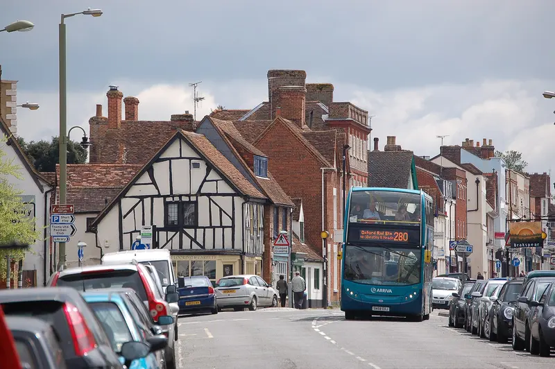 Thame's broad High Street lined with timber-framed and brick buildings, with parked cars and a bus
