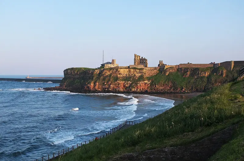 The ruins of Tynemouth Priory and Castle on a grassy clifftop headland above the sea