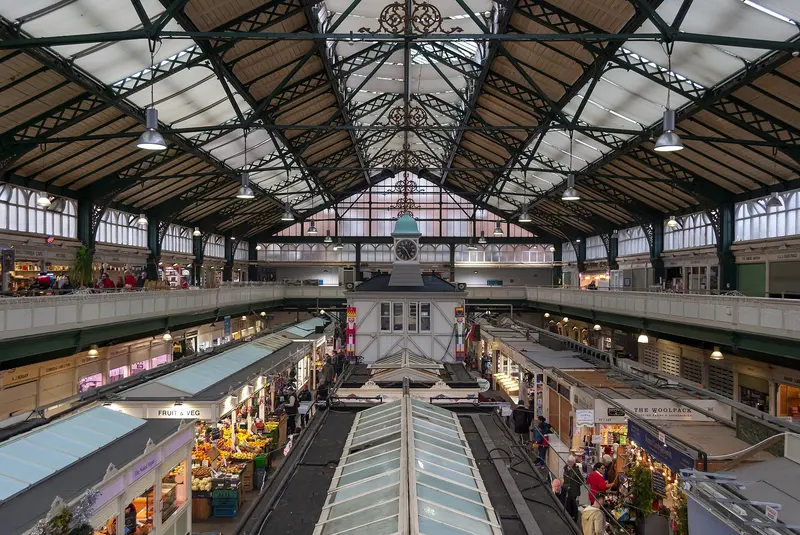 The interior of Cardiff Market seen from the upper gallery, with stalls under a glazed Victorian iron roof